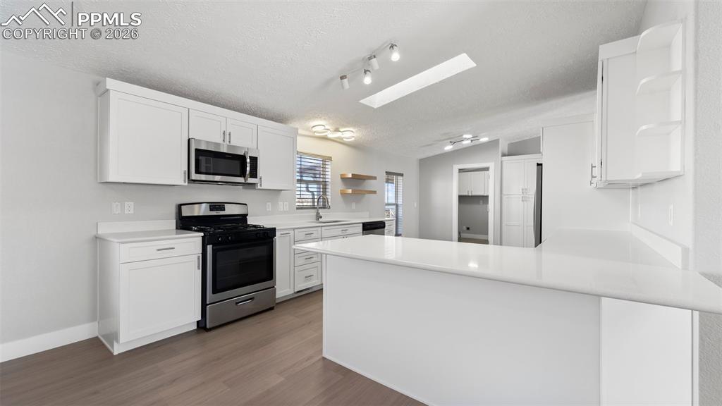 Image 39 of 50: Kitchen with white cabinetry, sink, stainless steel appliances, and kitchen