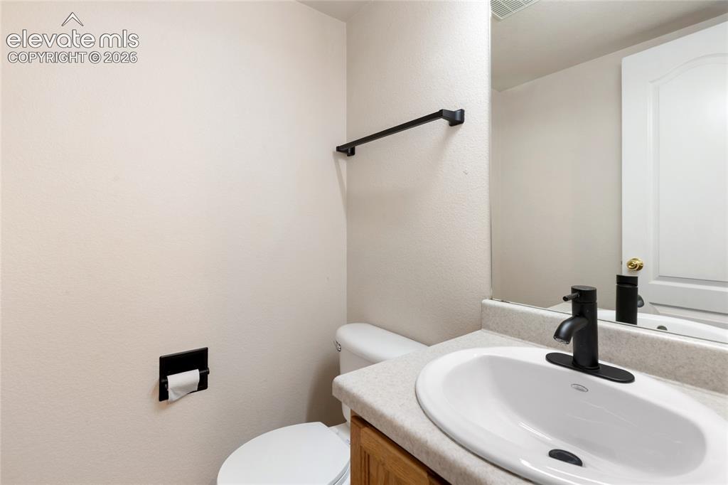 Image 15 of 38: Bathroom vanity with an oval sink, matte black faucet, and speckled counter