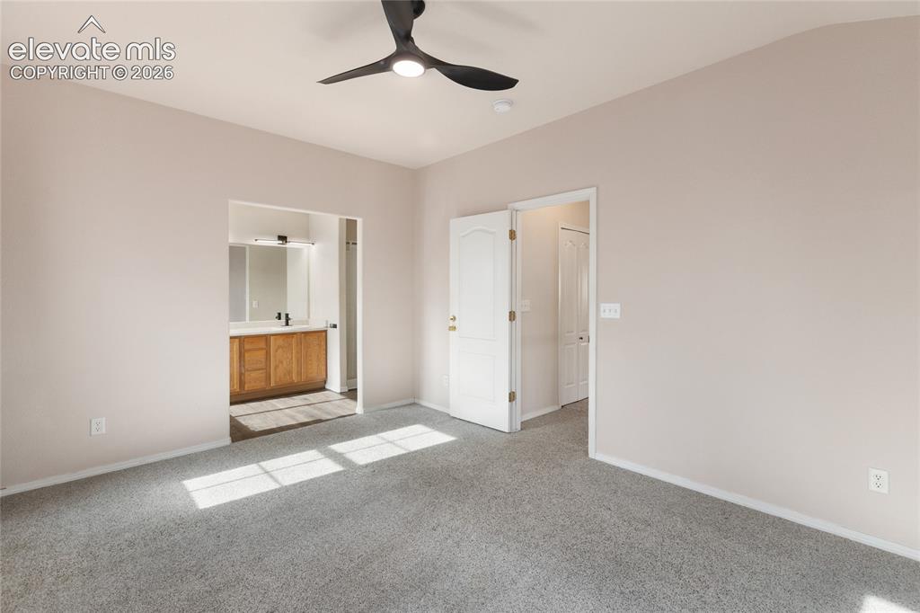 Image 17 of 38: Carpeted room with a modern black ceiling fan, featuring a doorway to a bat