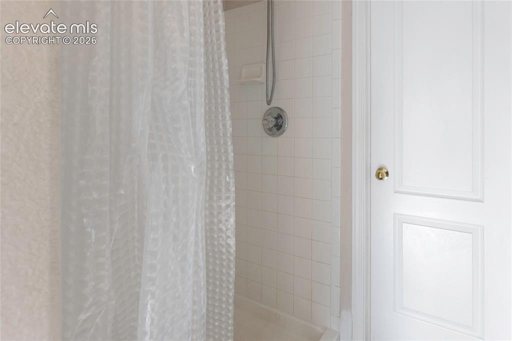 Image 21 of 38: Bathtub with white subway tile surround, polished chrome shower fixtures, a