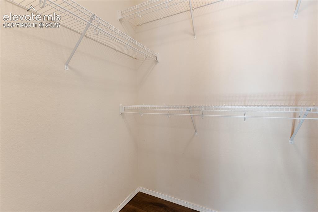 Image 28 of 38: Walk-in closet featuring wire shelving, multiple storage levels, and wood-f