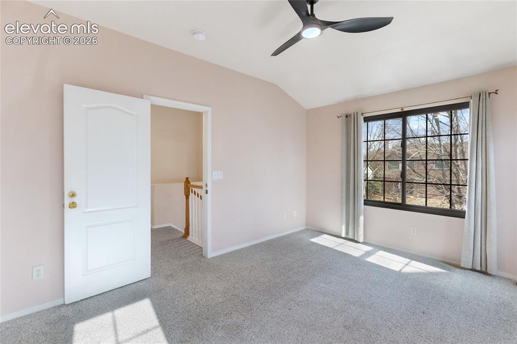 Image 29 of 38: Bright room featuring a vaulted ceiling and a contemporary ceiling fan