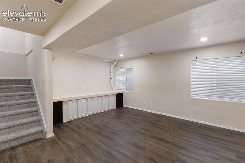 Image 30 of 38: Spacious room featuring wood-finish flooring, recessed lighting, and two wi