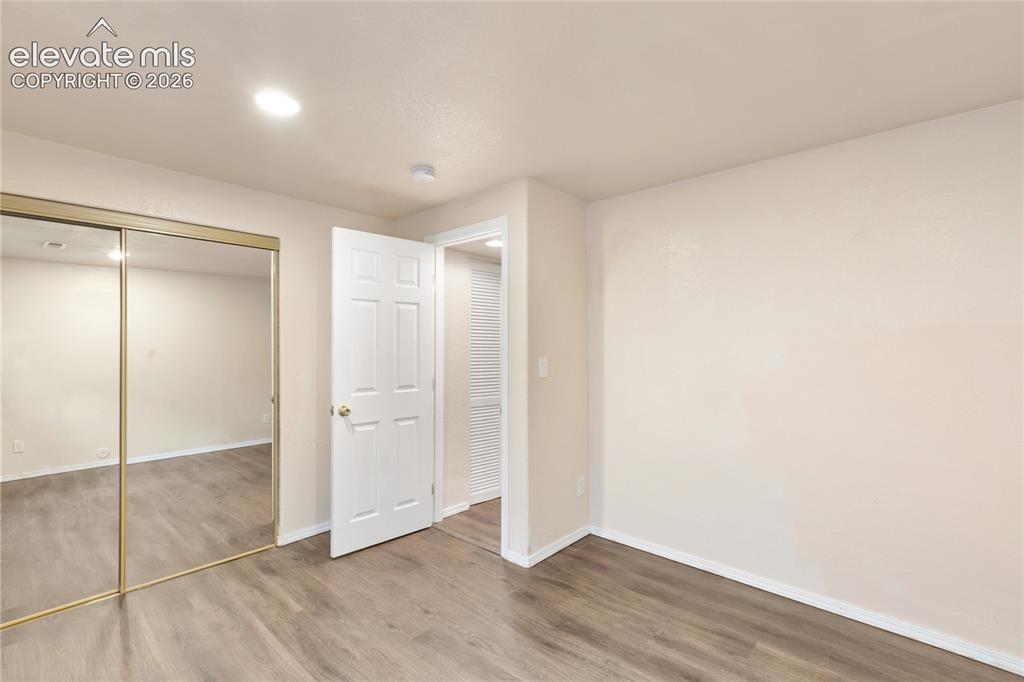 Image 35 of 38: Interior room with wood-finish flooring, light-colored walls, and a white b