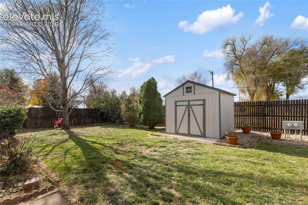 Image 36 of 38: Expansive backyard featuring a detached storage shed, mature trees, and a w