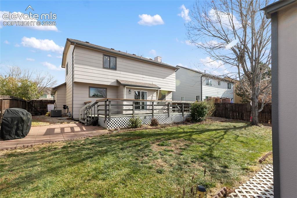 Image 37 of 38: Rear exterior featuring a multi-level deck with lattice skirting, a manicur