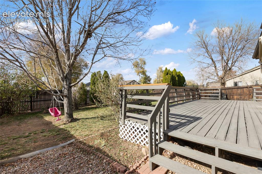 Image 38 of 38: Spacious outdoor deck with a gray finish, featuring a full railing and step