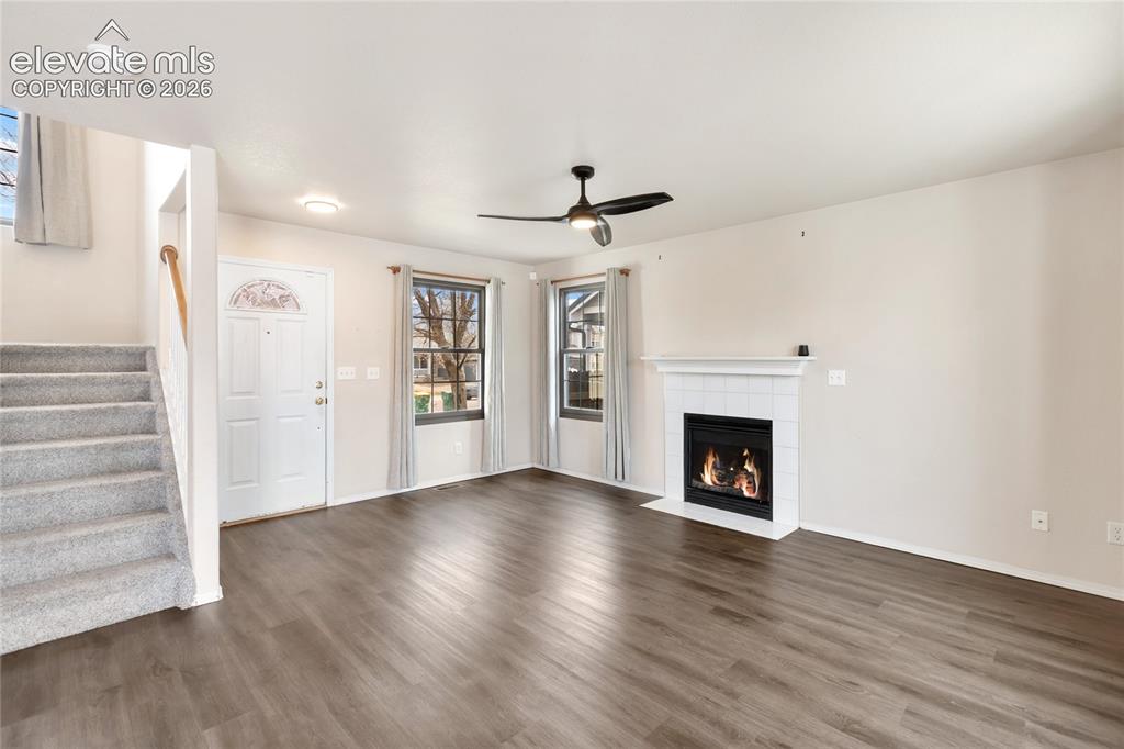 Image 6 of 38: Living area featuring a white tile surround fireplace with mantel, dark woo
