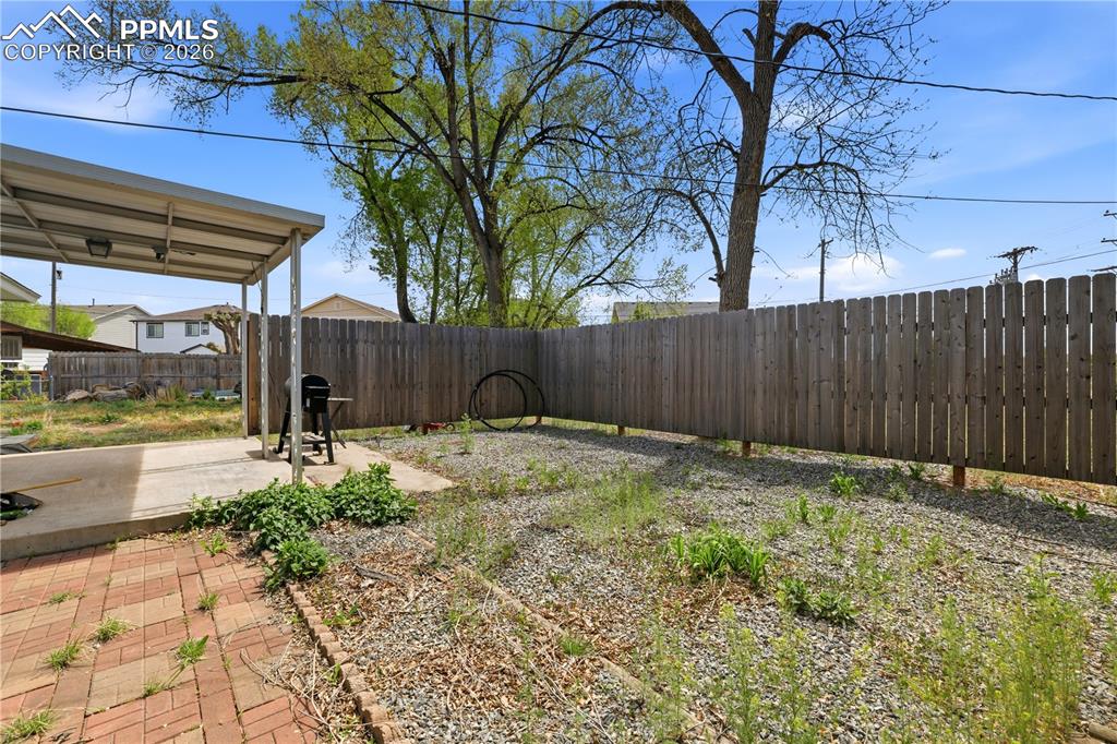 Image 14 of 19: The property includes a spacious backyard featuring a covered patio, a priv