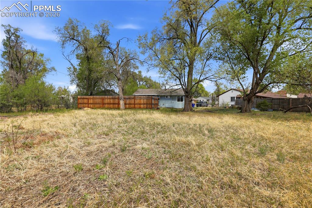 Image 18 of 19: The property features an expansive, level lot with mature trees and a parti