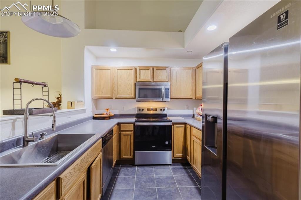 Image 19 of 35: U-shaped kitchen featuring light wood cabinetry, stone-finish countertops, 