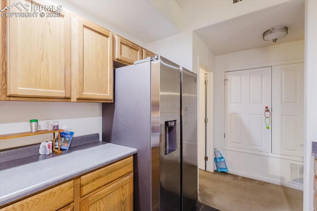 Image 22 of 35: Kitchen area featuring light wood cabinetry, a stainless steel refrigerator