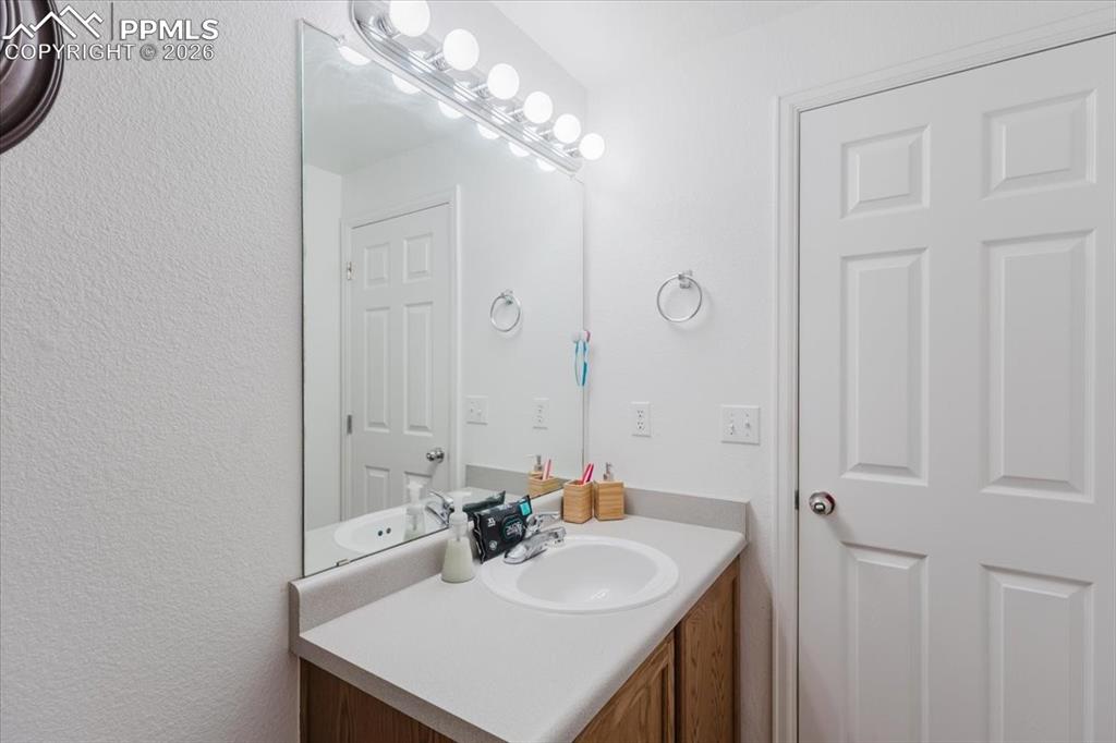 Image 24 of 35: Vanity featuring a single basin sink, light-toned countertop, and wood-fini