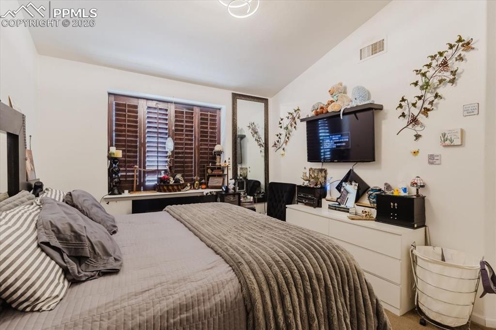 Image 27 of 35: Room featuring a vaulted ceiling and a window with plantation shutters