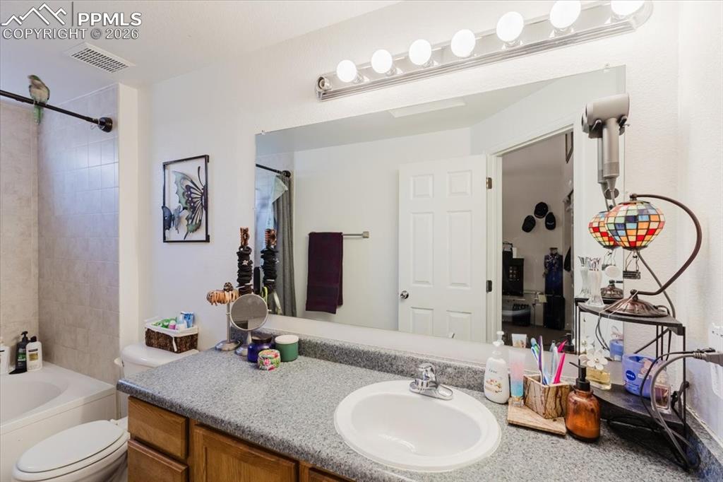 Image 30 of 35: Bathroom vanity featuring an oval undermount sink, speckled countertop, and