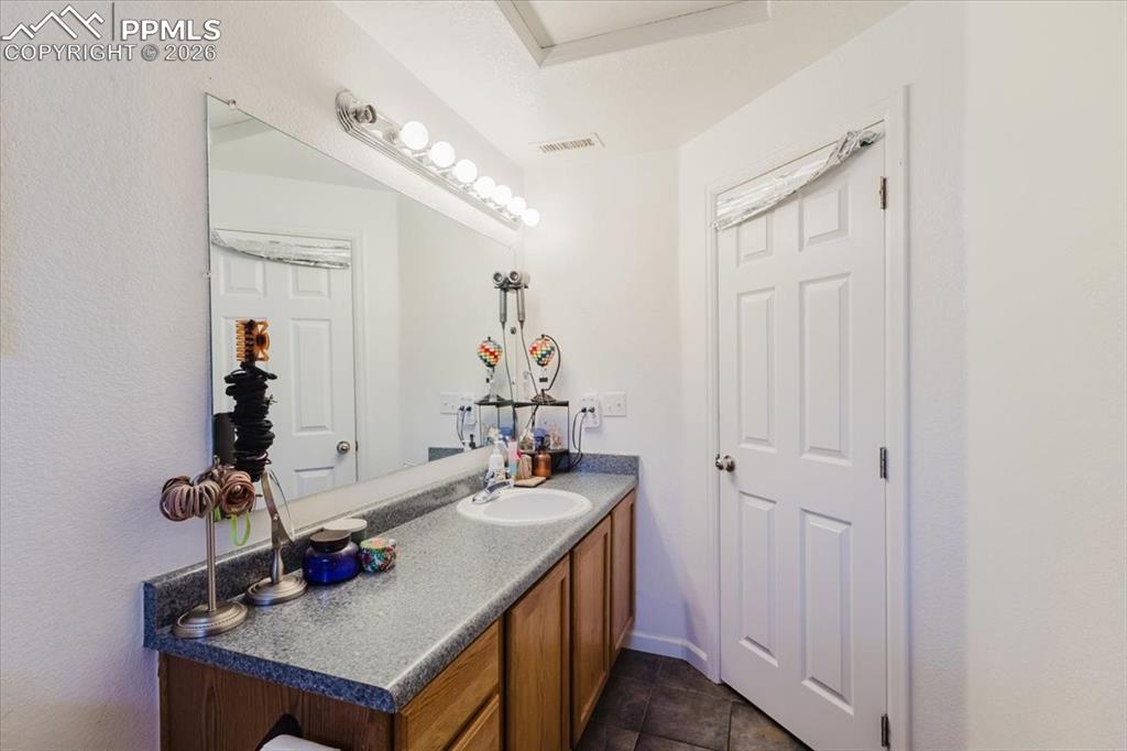 Image 31 of 35: Bathroom vanity featuring a single basin sink, durable countertop, and wood