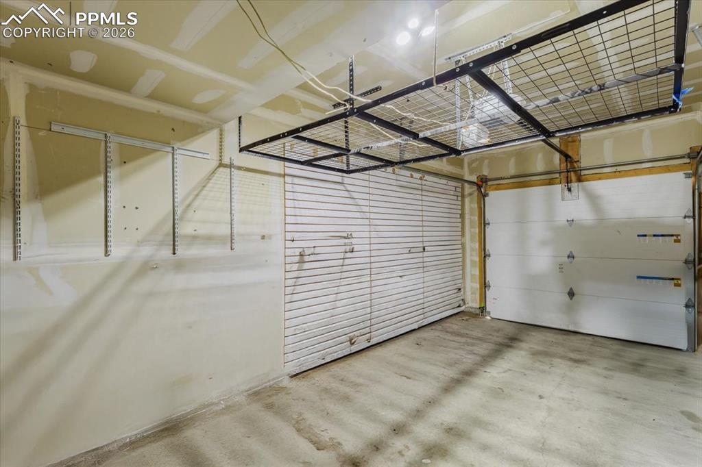 Image 32 of 35: Spacious garage featuring concrete flooring, an overhead storage rack, and 