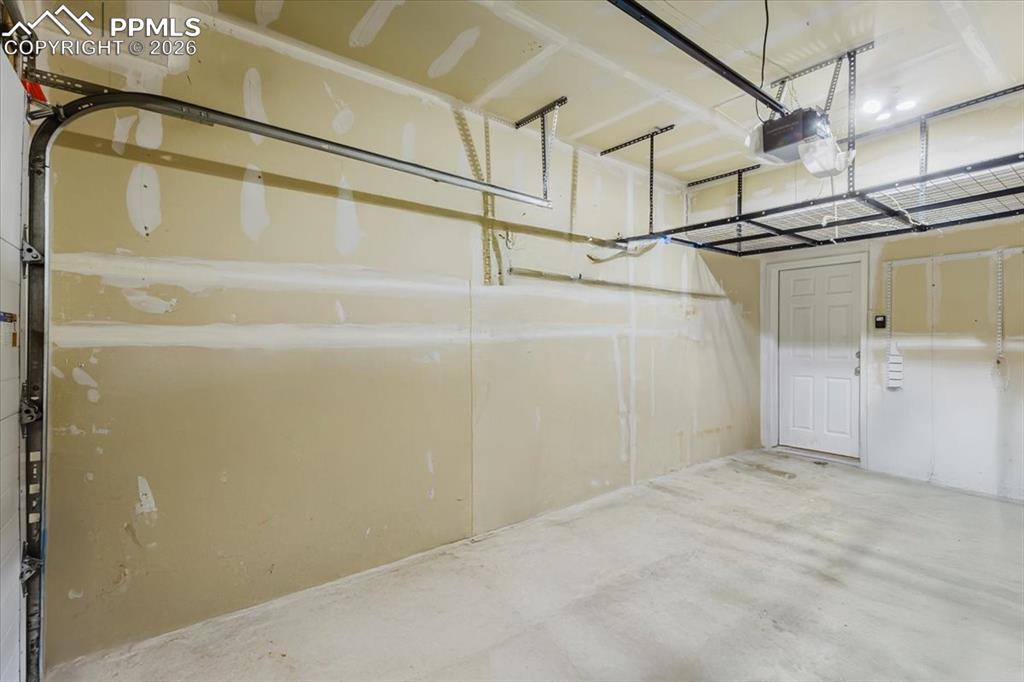 Image 33 of 35: Spacious garage featuring concrete flooring and neutral-toned walls