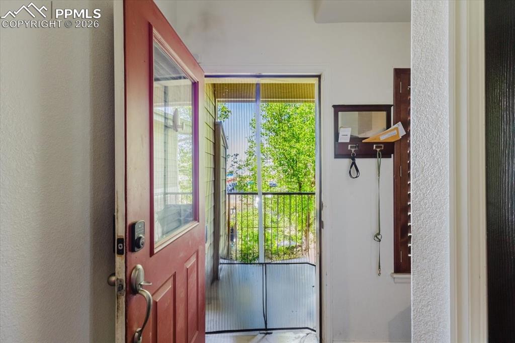 Image 34 of 35: Entryway featuring a red paneled door with an integrated glass panel, a sma