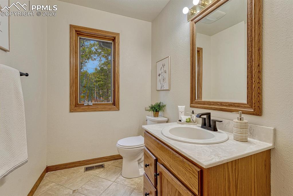 Image 11 of 50: Convenient Powder Bathroom with vanity and framed mirror.