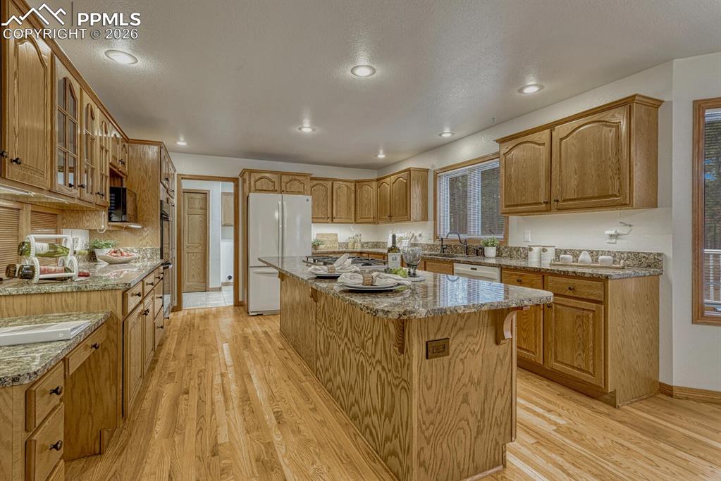 Image 19 of 50: The gourmet island kitchen showcases hardwood floors, rich wood cabinetry, 