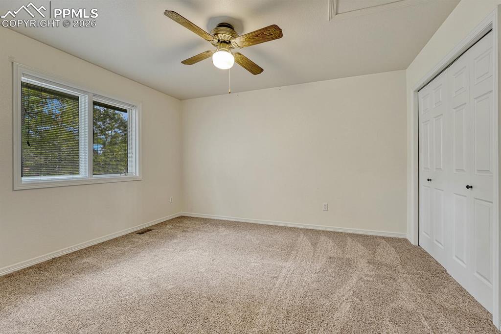 Image 24 of 50: Upper Level Bedroom with neutral carpet and lighted ceiling fan.