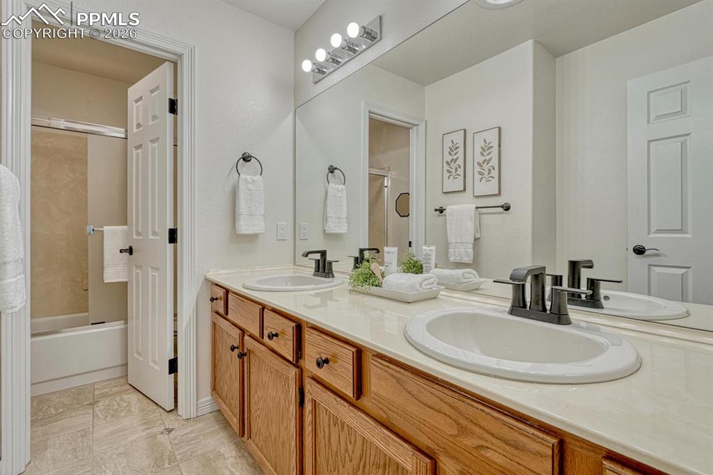 Image 26 of 50: Upper Level Full Hall Bathroom with dual sink vanity, mirror, and tiled tub