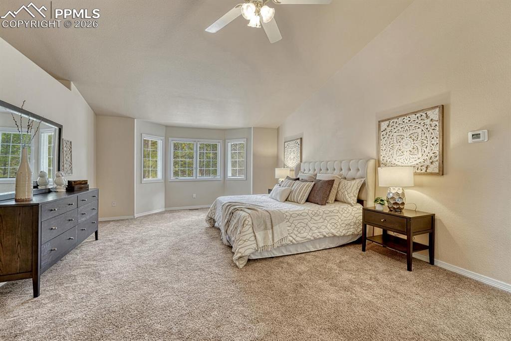 Image 31 of 50: The Primary Bedroom has neutral carpet, a lighted ceiling fan, and bay wind