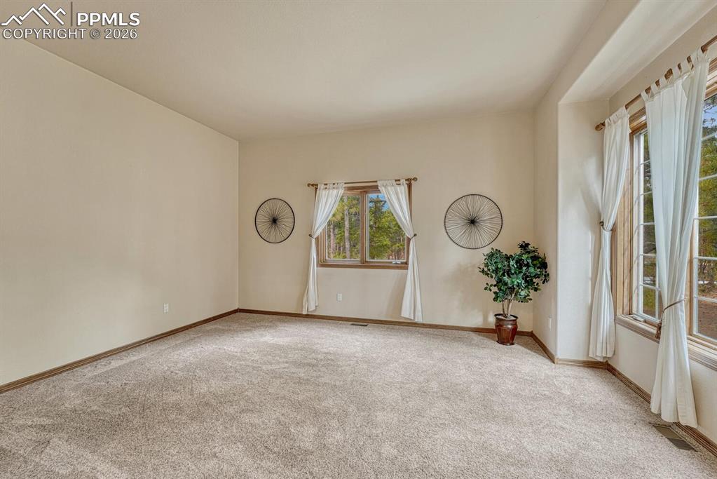 Image 5 of 50: Main level Formal Living Room with neutral carpet and large view windows.