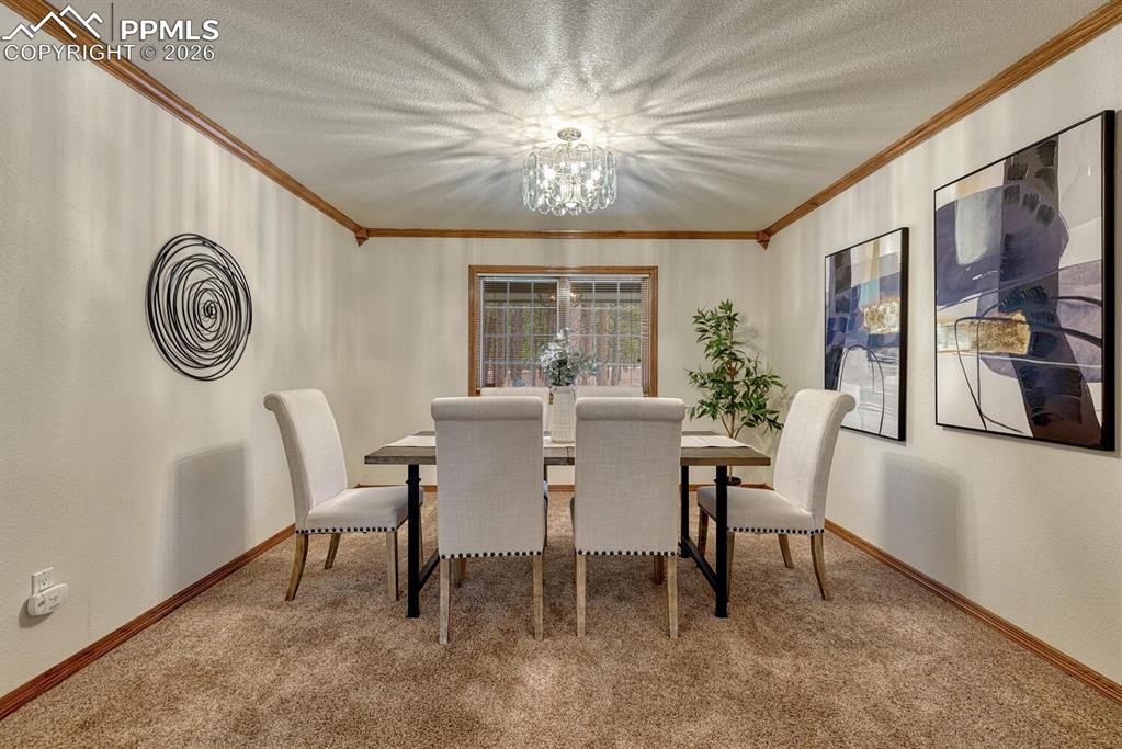Image 7 of 50: The Formal Dining Room features plush carpet, crown molding, & a beautiful 