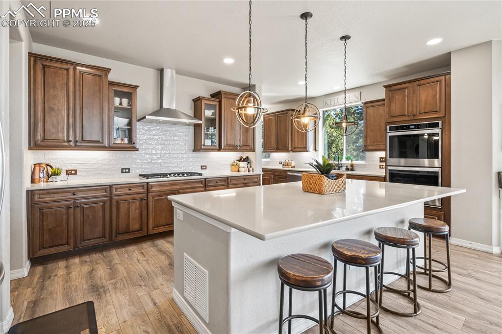 Image 10 of 50: Kitchen with wall chimney exhaust hood, stainless steel appliances, a cente
