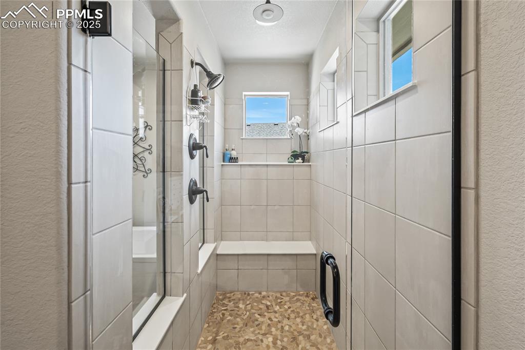 Image 21 of 50: Poured pan shower with seat, built-in shelving, and a Rain-head Showerhead