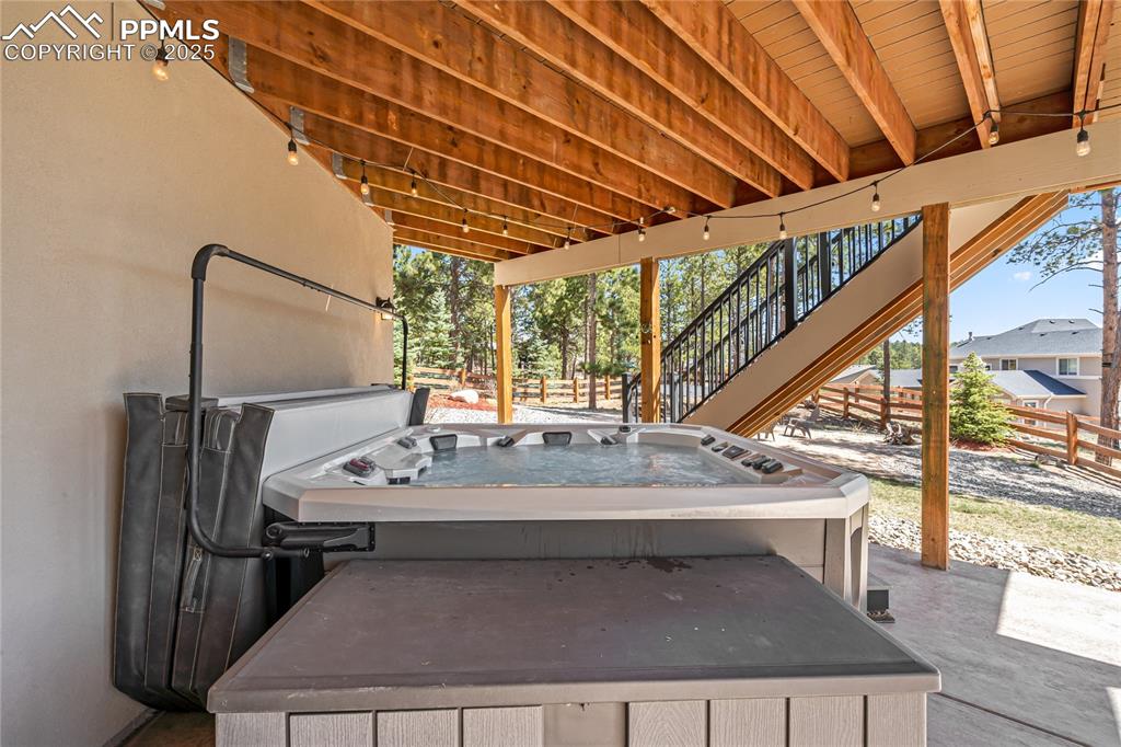 Image 42 of 50: Walk-out basement patio with 8-person hot tub and deck box for storage.
