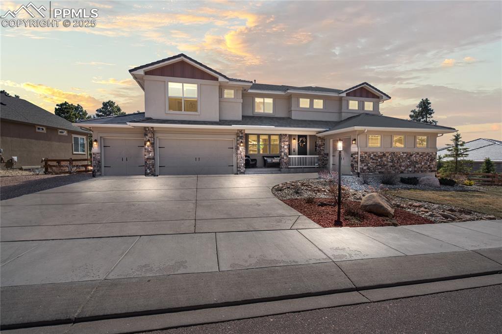Image 50 of 50: View of front of house with stone siding, a porch, concrete driveway, and 4