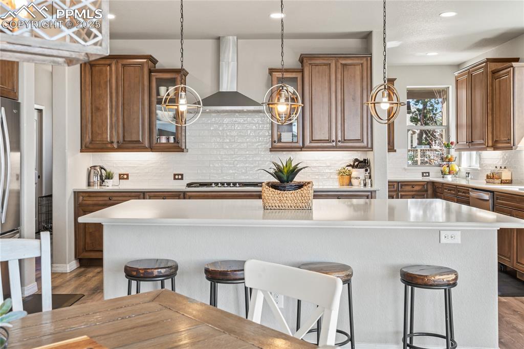 Image 8 of 50: Kitchen with light countertops, a breakfast bar area, a kitchen island, woo