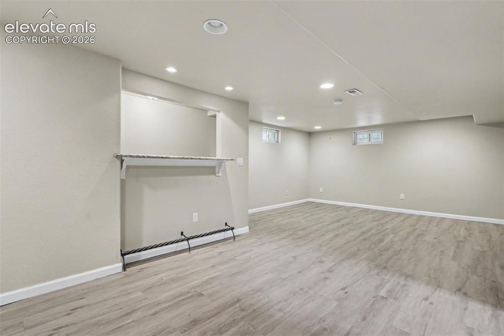 Image 16 of 36: Spacious room featuring wood-finish flooring, recessed lighting, and a buil