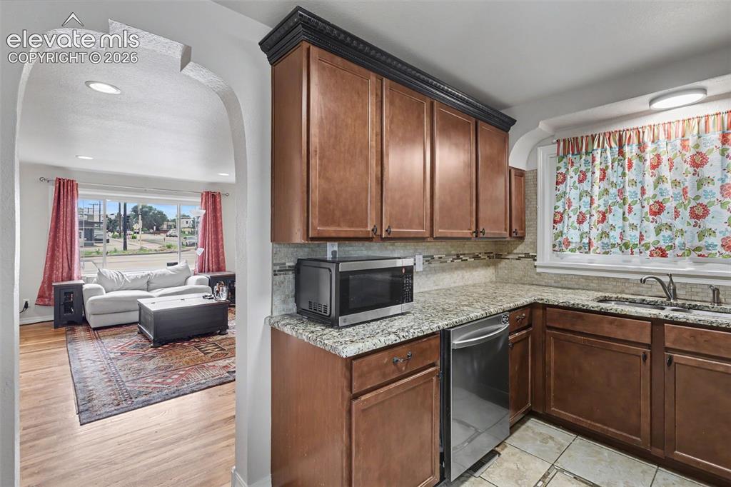Image 8 of 36: Kitchen featuring warm wood cabinetry, light granite countertops, and a sta