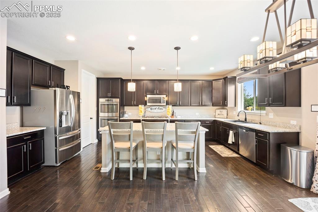 Image 11 of 46: Kitchen featuring a breakfast bar, dark brown cabinetry, appliances with st