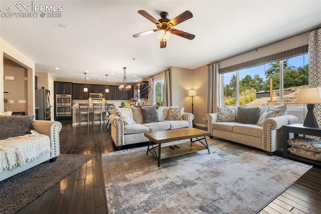 Image 15 of 46: Living area featuring dark wood-style flooring, a chandelier, and ceiling f