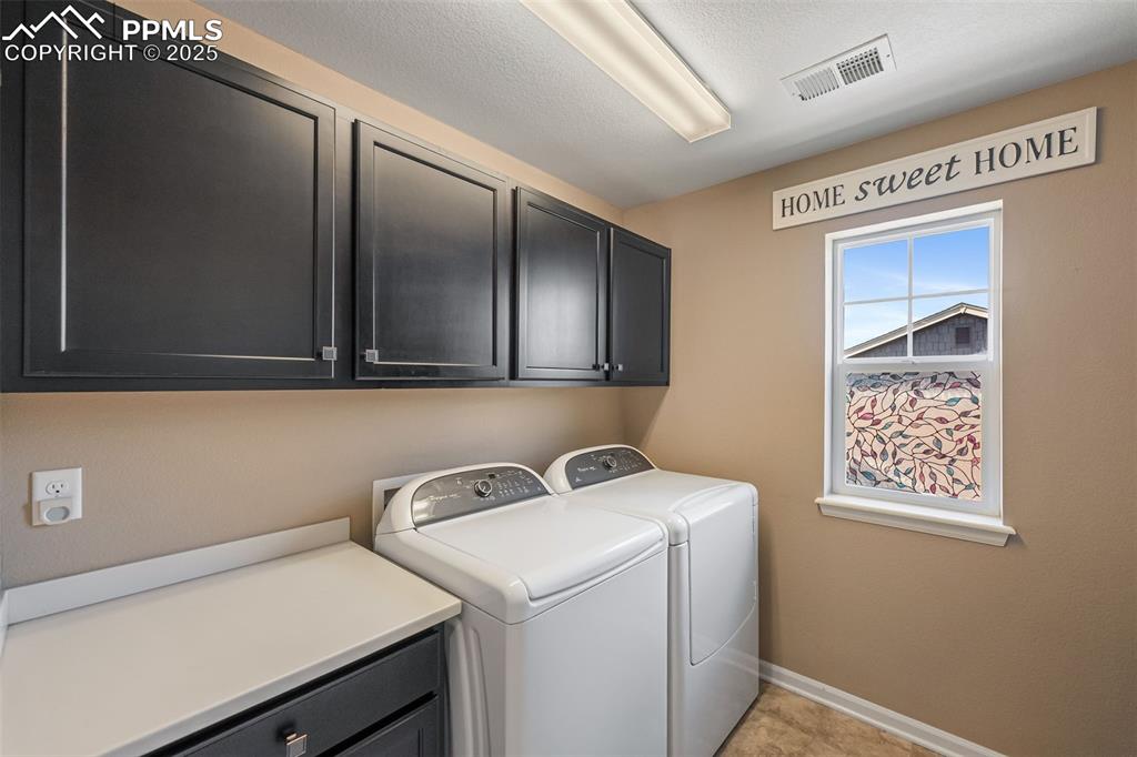 Image 28 of 46: Laundry area featuring cabinet space, washing machine and dryer, and a text