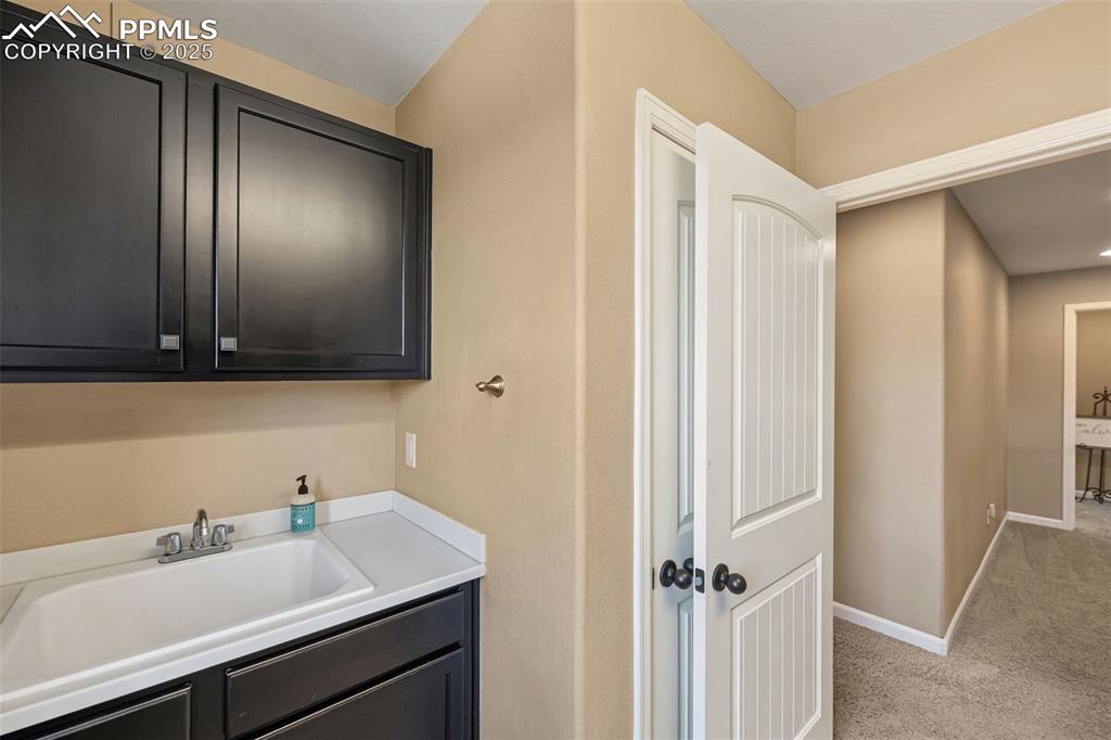 Image 29 of 46: Laundry area with a sink and light colored carpet