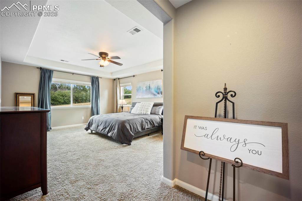 Image 32 of 46: Bedroom featuring light carpet, a raised ceiling, and ceiling fan