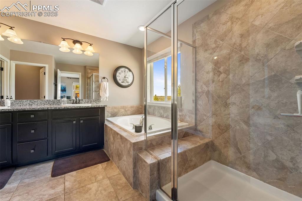 Image 33 of 46: Bathroom with vanity, a bath, a stall shower, and light tile patterned floo