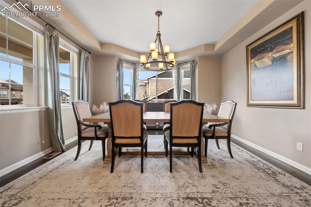 Image 4 of 46: Dining space with a raised ceiling, a chandelier, and wood finished floors