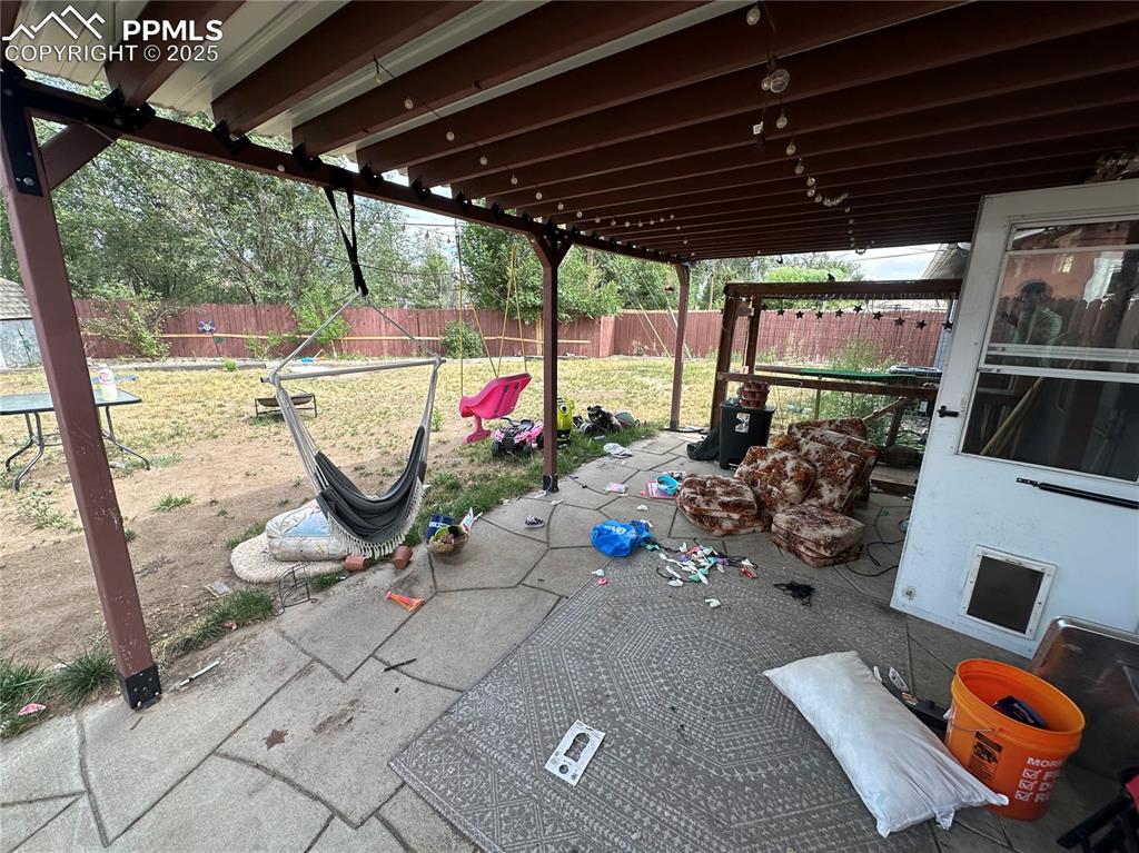 Image 11 of 13: Fenced backyard with a patio