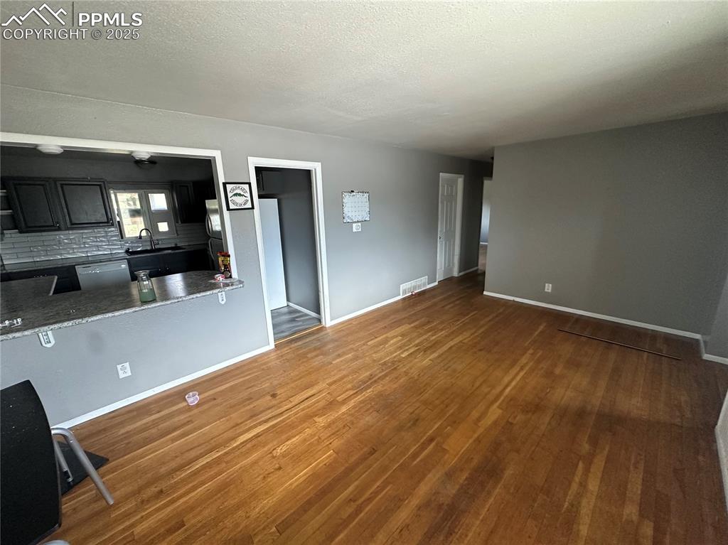 Image 2 of 13: Unfurnished living room featuring a textured ceiling and wood finished floo