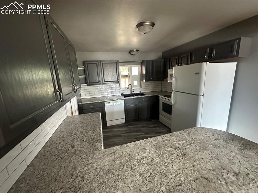 Image 3 of 13: Kitchen with white appliances, backsplash, and light stone countertops