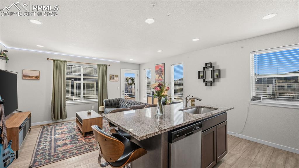 Image 13 of 37: Kitchen featuring light stone countertops, open floor plan, dishwasher, an