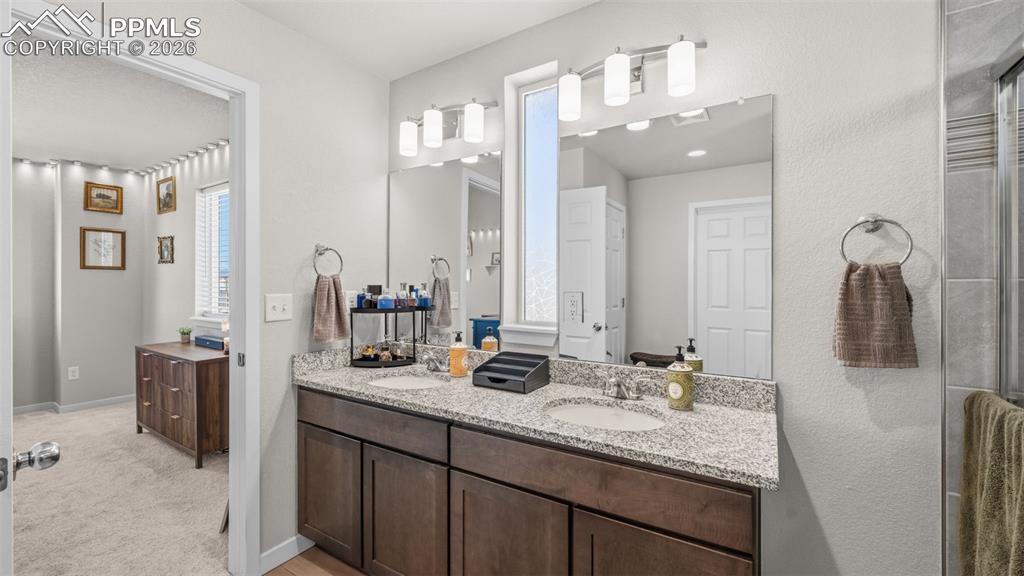 Image 21 of 37: Bathroom with double vanity, a stall shower, and light carpet