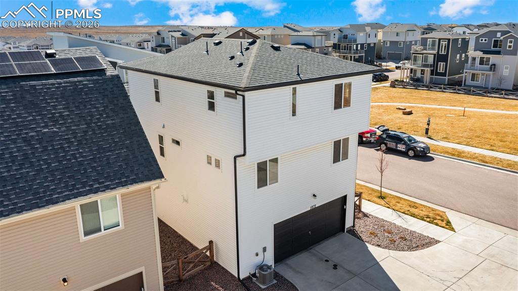 Image 28 of 37: View of side of home with an attached garage, roof with shingles, concrete 